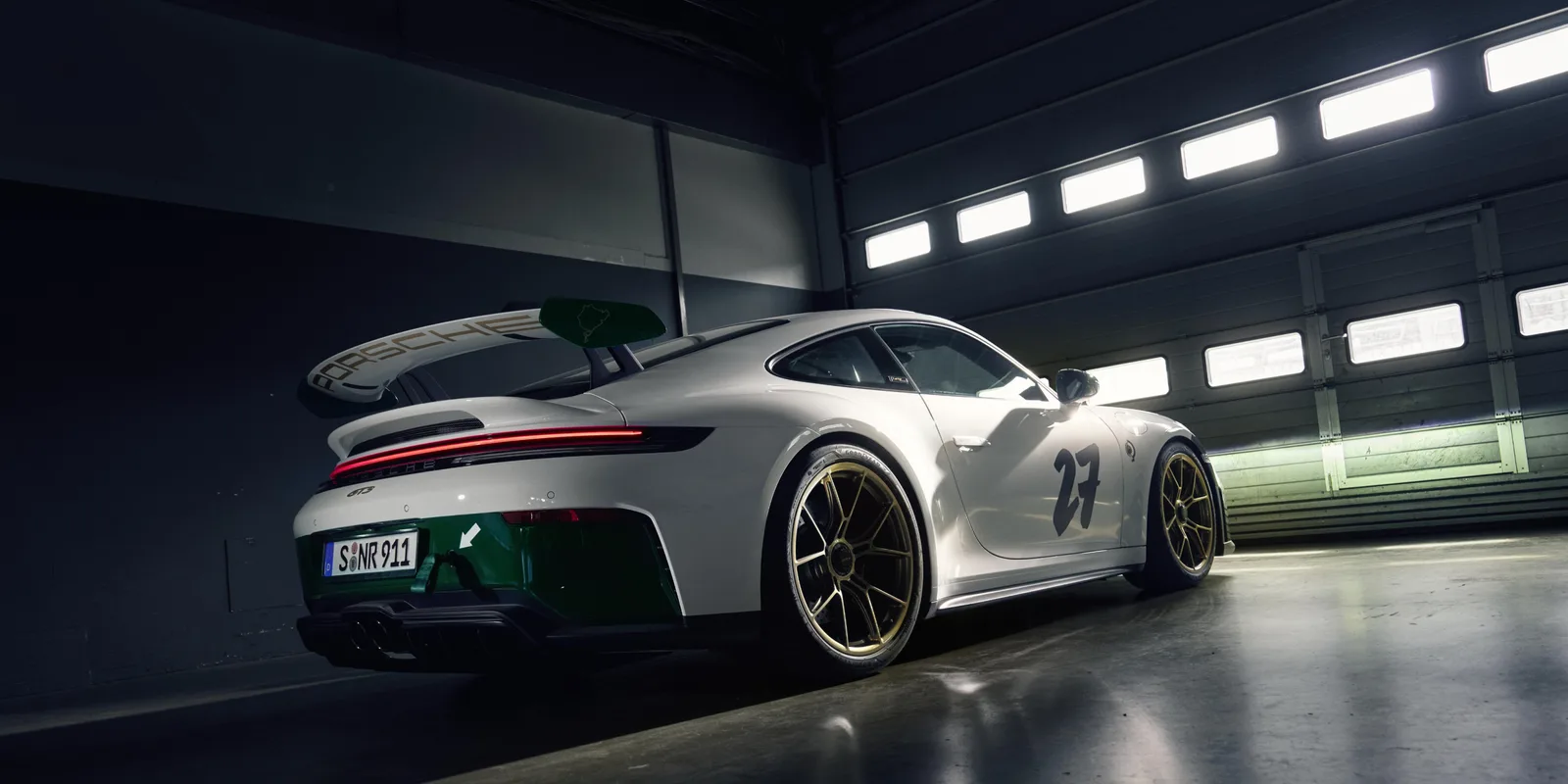 Porsche 911 GT3 100 Jahre Nürburgring, ujęcie 3/4 z tyłu w boksie, zielony tył i złote felgi